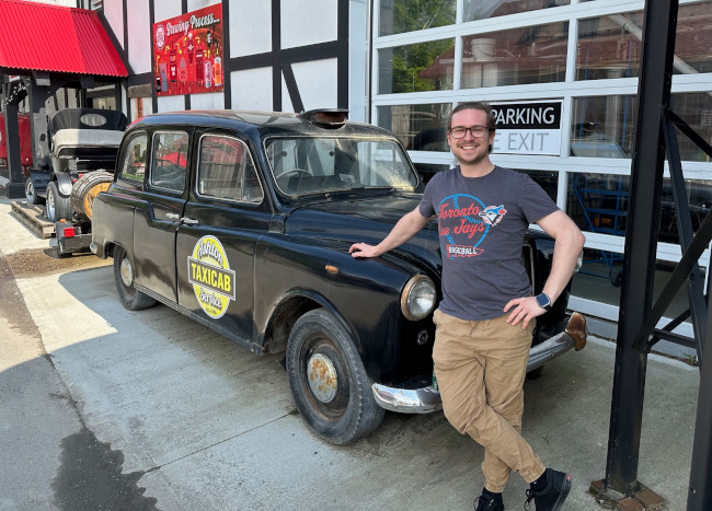 The author with an old looking black taxi car with suicide doors.